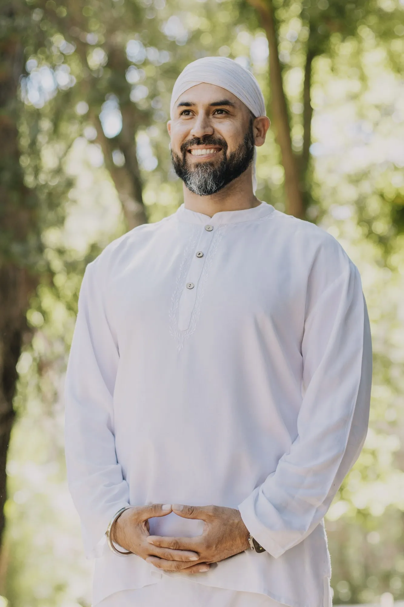 Italo de pie en el bosque, vestido de blanco, sonriendo a la cámara.