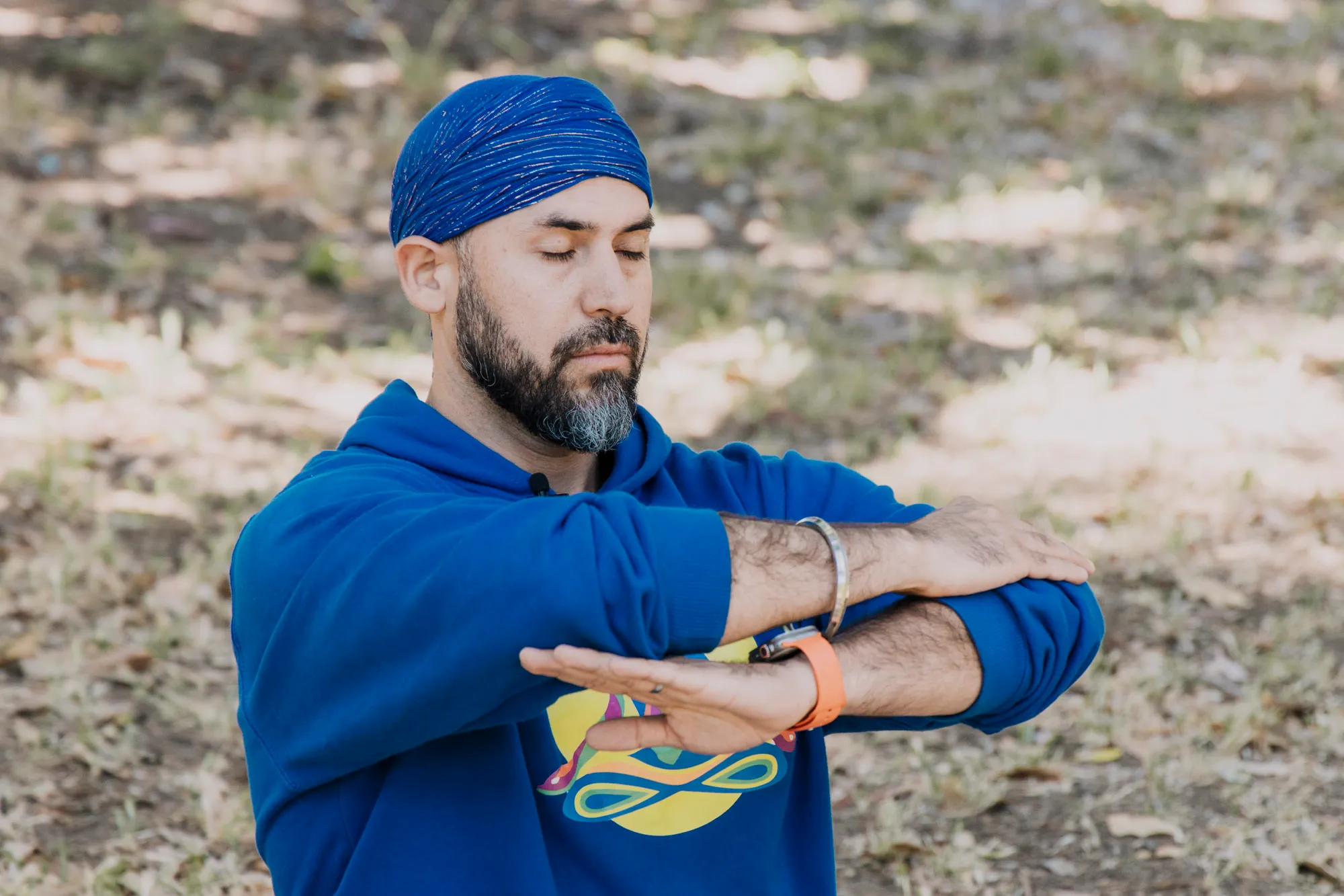 Italo con turbante azul y los brazos cruzados frente al pecho, con los ojos cerrados.